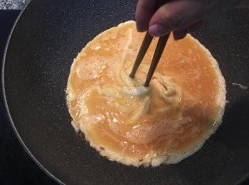 step3: 薑煎香後取出，加入剩下的麻油，開中小火並倒入蛋汁，如想要做有螺旋狀的煎蛋，就是拿ㄧ枝筷子從最邊緣往中間移動後轉動鍋子，另一枝筷子從對角邊緣ㄧ樣往中間移再次回轉鍋子。 （當然也可以直接倒入蛋液煎熟就好喔～）