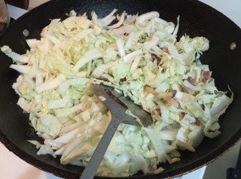 step6: 炒香後再加入黃芽白，雞粉及鹽放最頂，煮大約5分鐘，待黃芽白變成半透明，把年糕放在黃芽白上。
