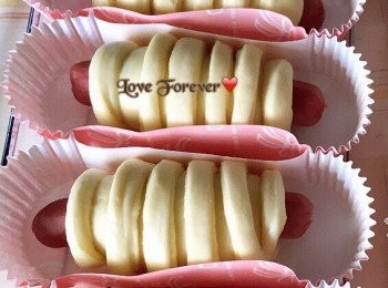 step5: 麵團靜置後，鬆弛已分割的麵團，開始造型，擀成橢圓形片，一邊卷入一條腸仔於1/3位置，用刮刀將其餘2/3切割成條狀，用刮板壓扁條狀尾，然後卷好其餘的2/3，收口朝下。