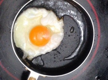 step7: 把平底鑊燒熱，下油（油要多一點），下一隻蛋煎成荷包蛋後鋪上拌麵即可