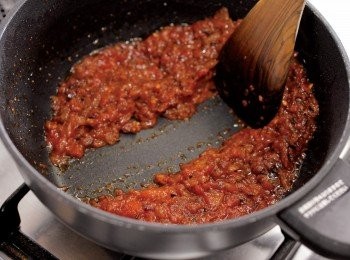 step9: 放入番茄罐頭→轉大火，加入番茄罐頭，同時用木匙搗爛，炒至水分完全蒸散（當木匙鏟動時，醬料不會流回木匙刮過的地方就可以了）。