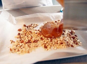 step7: 拖肥杏仁脆糖:不透鋼盤舖上牛油紙，灑上果仁及朱古力碎粒。把剩下的拖肥糖漿倒於碎粒上