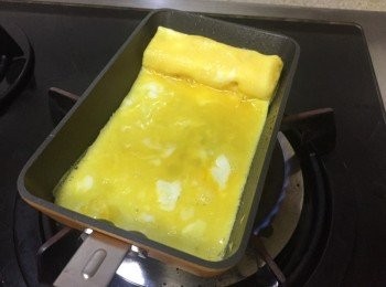 step4: 卷向上置好，就可以再用廚房油紙抹一層油，加入2匙蛋汁，注意將蛋汁倒向卷起的蛋下，(可用筷子提起少許卷起的蛋)，讓2層蛋黏在一起