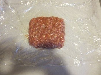 step2: 在枱上墊一張烤盤紙後(baking paper/parchment paper)放上一些豬肉，猪肉上面再包一层保鮮紙。