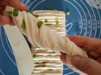step6: 接著就像扭毛巾一樣上下往反方向扭、 收口尾端放下， 便可完成一個蔥花包