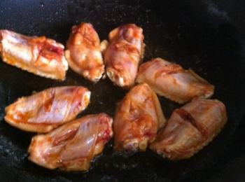 step2: 鍋裡倒油，放薑片，小火煎至雞翅兩面8成熟，然後下鹽，再加一點兒醬油和水，翻炒幾下。