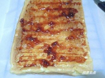 step11: 出爐後移到桌上將旁邊的烘焙紙撕開散熱放涼,完全放涼後將蛋糕翻過來,底部的烘焙紙撕開,底部墊著撕下來的烘焙紙,烤面朝上,在蛋糕開始捲起處用刀切3-4條不切到底的線條,將草莓果醬適量均勻塗抹在蛋糕表面