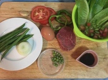 step1: 蒜頭略拍；四季豆去頭洗淨；洋蔥去頭尾剝皮；青甜椒取中間段切成圈狀，除籽；剩下的青椒切小丁與生菜放ㄧ起；蕃茄取中段切成圈狀，剩下的除籽切小丁與生菜放一起。美生菜洗淨，與青椒丁和蕃茄丁一起用可飲用的水洗淨、瀝乾後放入冰箱冷藏。牛里肌以海鹽和黑胡椒粉兩面抹勻。