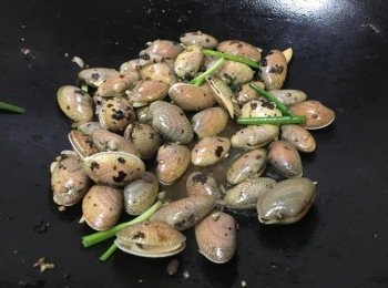 step4: 原鑊先加入乾蔥頭爆香再加入餘下一半的豆豉蒜蓉中大火炒香，再加入瀝乾水份的花甲快炒, 灑上蔥段