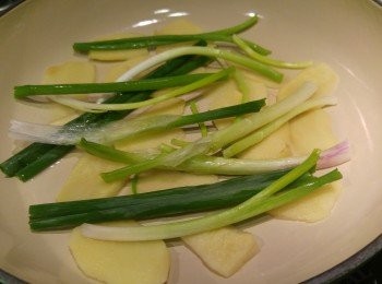 step2: 今次用鑄鐵鍋計算時間, 先鋪薑片和蔥段落鑊, 用中細火蓋蓋煮兩分鐘, 然後熄火把雞件鋪在蔥段上, 再加兩湯匙水, 用中火蓋蓋煮6分鐘熄火焗10分鐘。(期間勿開蓋。)