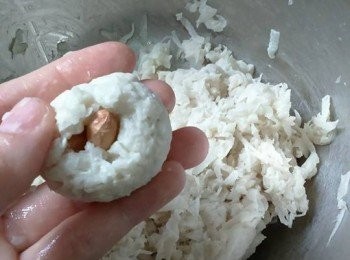 step5: 取適量混合好的蘿蔔絲於手中，加入2粒花生，用手掌心按壓成圓形，