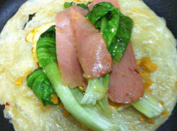 step4: 麵餅放入鍋內再煎一小會，然後把雞蛋火腿，青菜，全部放都麵餅上。