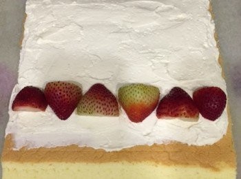 step8: 蛋糕左右兩邊切走修飾，上下兩邊用刀向外斜切 （之後容易捲的）。用刀在蛋糕上左至右打橫界坑，約2吋一條（不要界斷！）（之後容易捲）。將忌廉餡平均塗抹在蛋糕上，蛋糕上下邊留3cm 不用塗忌廉。在近自己的蛋糕邊忌廉上，放自己喜愛的水果。