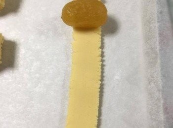 step2: 取出少量餅皮，放入唧筒內，準備焗盤，焗盤上放上焗爐紙，將唧筒頭有曲線的那邊向下，唧出一整條餅皮(每個鳳梨卷的皮重量約11g)，約留2.5cm位，放上已搓成圓柱體的菠蘿餡，將剛才留起的2.5cm餅皮蓋上餡料上，亦預計尾部將需要的餅皮，用刀切斷；