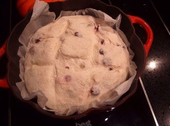 step9: 預熱完成後將鍋子取出(此時鍋子很燙請小心),取起蓋子放一旁,連同將烘焙紙及麵糰一起放入鍋裡,在麵糰表面用篩子濾網灑上少許的麵粉,用刀子快速在麵糰上劃出斜紋(幫助麵糰在烘烤時膨脹定型),蓋上鍋蓋放入烤箱烤25分鐘。25分鐘後將鍋蓋取出,再烘烤10~12分鐘至表面呈金黃色即可。