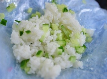 step2: 利用乾淨得棉布套上塑膠袋包覆，鋪上一層有機米飯，放上少許橄欖油及小黃瓜丁均勻戳柔再鋪平