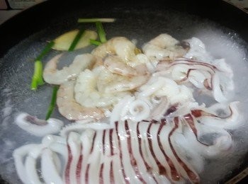 step5: 鍋倒入水煮滾，加入兩片薑、蔥段，倒入魷魚、海蝦出水30秒；撈起洗淨、瀝乾水備用