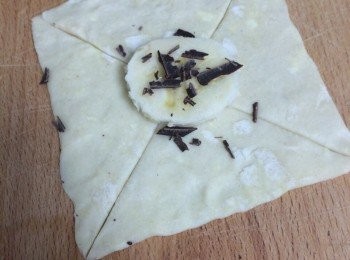 step2: 酥皮切成正方形（不要太厚）。從四角往中心切十字，不要切盡，中間需留有大約1元硬幣(=2.5cm) 空間，然後中間放香蕉片1塊及灑上朱古力