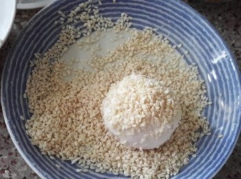step5: 在煎堆表面沾少許水，再沾滿白芝麻