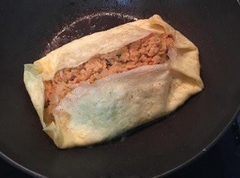 step8: 用鍋鏟將四邊摺起定型後就關火,並用鍋鏟直向鏟起,再將蛋包飯翻放在盤子上, 吃時在蛋皮上淋上適量蕃茄醬做裝飾.