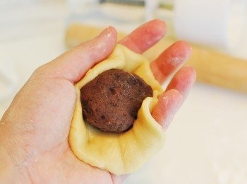 step12: 將麵皮放在掌心，慢慢包入一份豆沙餡，收口捏合