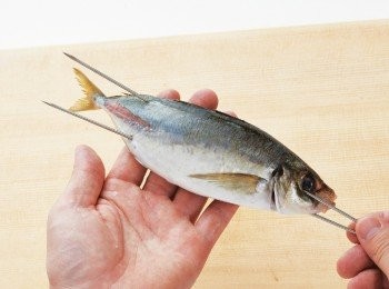step4: 將另一根鐵籤由魚口刺入，並從第一根鐵籤的下方（腹部靠近魚尾處）穿出。從表面（頭部朝左、腹部朝內時向上的那一面）看不見鐵籤的狀態稱為「穿刺法」，烤出來的魚姿尾部上揚，十分美觀。
