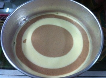 step4: 然後將混合好的麵糊分開兩份，其中一份加入可可粉攪拌均勻。取出烘培模底部加入烘培紙，然後麵糊粉3次加入，麵糊從模型中間倒入，一份可可麵糊，一份原味麵糊順序加入做完為止。然後再表面上輕輕的畫上線頭，形成花型。