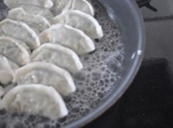 step4: 有平底鍋最好，上鍋加熱，倒入一點點兒油，把餃子整齊得擺放好,不加水煎30秒。再倒入水，基本上沒過餃子一半，蓋上鍋蓋燜5分鐘。水漸漸乾了時，再加一點油，均勻轉動鍋，煎30秒-1分鐘，以不要焦糊為宜。最後把準備好的麵粉水汁倒入，蓋蓋子繼續燜到水汁略變焦黃。這時餃子就煎好了。