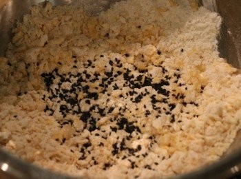 step2: 放入黑芝麻繼續搓，再加入1大匙清水搓匀，若麵糰很乾可加另1大匙水再搓匀。