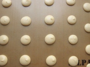 step5: 靜置麵糊時,當表面摸起來有一層薄膜不沾手的狀態即可開始烘烤。靜置時間會依空氣濕度而不同(當天濕度50%放40分鐘),將烤箱預熱180度c,進烤箱後調降為160度c,約5分鐘後裙邊會產生,再將烤溫降為130-140度c續烤至熟。全程約17分鐘，當手輕輕捏住杏仁圓餅不會晃動即代表烤熟。出爐後放涼即可。