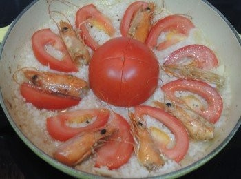 step3: 加入白米、清水、鹽和少許黑胡椒碎攪拌並煮滾，在中央放上一個蕃茄，扇形圍着蕃茄放上蕃茄片，加入炒香的蝦頭，加蓋轉小火煮10分鐘。