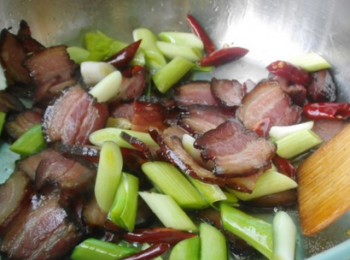 step6: 放臘肉入炒鍋，翻炒至出油，下薑片，辣椒，蒜苗梗翻炒。