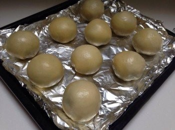 step7: 接著將6.的皮橫向壓扁桿成圓形狀邊緣桿薄一點,包入4.的烏豆沙蛋黃,每一顆都要捏緊喔,底部朝下放烤盤上!