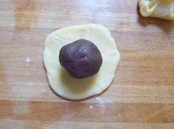 step17: 將麵糰擀成圓形薄片,光滑面在外,中間放上烏豆沙內餡,利用虎口將麵糰收口朝內捏緊,成為一個圓形。