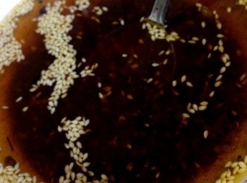 step5: 炸好的热油倒入的碗中盛有熟芝麻，辣椒粉、盐、花椒粉放入小碗中迅速用筷子搅匀，然后用一个盘子盖住碗口，焖一会，可使红油颜色鲜艳，味道香浓拌匀备用。