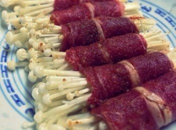 step3: 將醃好的肥牛攤開，放適量的金菇由一邊慢慢捲上