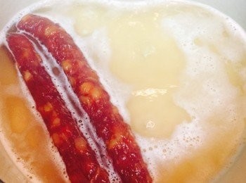 step3: 醃雞時先煮飯。米和水比例約1 : 1.1，放入鑄鐵鍋用中火煮至微滾見魚眼，放入臘腸後加蓋轉小火煮15分鐘。熄火焗10分鐘。