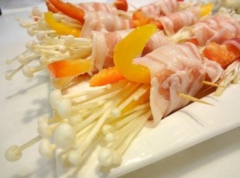 step2: 3~4片的培根鋪平，放上紅椒、黃椒和金針菇，輕輕的捲起，前後各用１支牙籤固定。