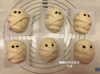 step6: 將長麵條裹在橢圓形麵糰上，用筷子沾水，在沾水處放上眼睛，放在裁好的烘培紙上