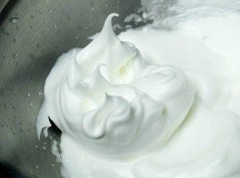 step3: 在另一碗內，用電動打蛋器打發蛋白，打至出現大泡泡，加一小匙檸檬汁（*這有助打發蛋白）然後分3次慢慢加入糖。打發至乾性發泡狀態（*打好的<span class="group_2">蛋白霜</span>拉起時呈"不下彎"的尖挺狀）