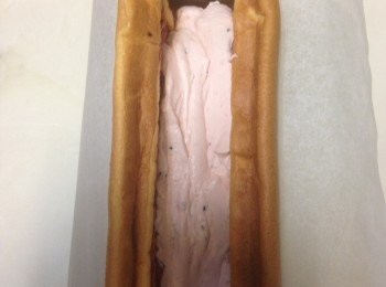 step7: 將蛋糕體裁成適合放入鐵盒大小後，在內部先抹上一層紅龍果果醬，再填入約1/2份量的內餡(中間部位)後，放入鋪好料理紙的鐵盒。