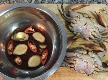 step2: 清洗螃蟹，用刷子將螃蟹殼都刷洗乾淨，接著拿尖刀從蟹心刺入，便可以除去綁繩，刷洗蟹腳和螯，並剪去腹部和蟹腸。取一小鍋放入薑片、辣椒和黃酒。同時煮滾蒸籠的水。