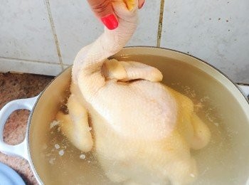 step3: 準備一個深鍋，中至大火煮滾一鍋水。捉著雞頸位置，水滾後將雞身浸入水中。待水再滾起時將雞拿起，盡量讓雞肚中的血水流出。重覆浸雞再拿起去血水的動作共三次。