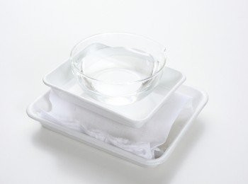 step1: 將豆腐包入抹布後置入長盤，上方放置鎮石，靜置脫水約30分鐘。鎮石的重量約與豆腐相同，可先將裝水的小碗放入長盤作為鎮石，受力平均之下，豆腐的形狀較不會走樣。