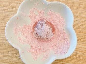 step5: 取出約一湯匙的粉糰，把它按平，包入草莓朱古力波，然後收口，再沾上防潮草莓糖霜粉防黏。
