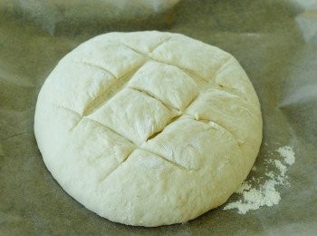 step6: 將麵團放在鋪有烘焙紙的烤盤上，蓋上毛巾，放在室溫靜置一個小時。然後用鋒利的刀在麵糰表面劃數下