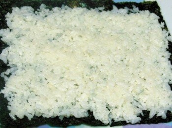 step3: 壽司海片入乾鍋，烤一下鋪於竹捲上 ，將約半碗的白米飯盡量壓緊平鋪在海苔片上，米飯要一邊鋪平一邊壓緊， 壓好厚度約0.5~0.7公分 。