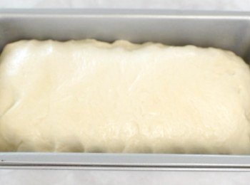 step5: 將麵糰放在灑有麵粉的枱上，用手按壓麵糰，排出空氣，將麵糰做成長形，放入塗有油的焗盤內，再蓋上保鮮紙，靜置30分鐘作第二次發酵