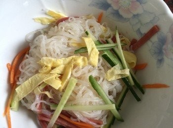 step5: 取一容器將蒟蒻春雨、小黃瓜、蛋片、火腿片、紅蘿蔔一起放入，使用筷子將<span class="group_1">食材</span>撥均勻。