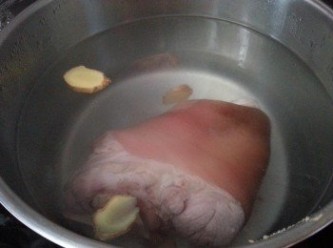 step3: 煲一煲水，放入數塊薑片以大火煮滾，加入豬手，水的高度要蓋過豬手，加入雞粉2湯匙,加蓋以大火煮半小時，轉慢火煮炆1.5小時至豬皮腍及肉熟透，取出豬手先放涼